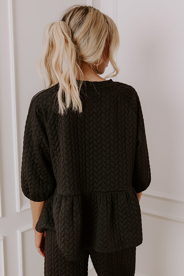 Quilted black lounge set with three-quarter sleeves, peplum detail, and wide-leg pants, combining comfort and style for winter.