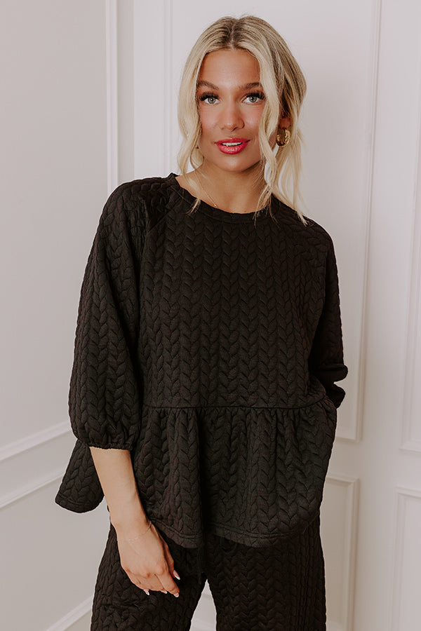 Comfortable and chic black quilted lounge set featuring a flowy peplum top and relaxed pants, perfect for winter days.